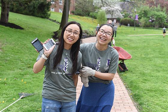 Photo of two international students on Chatham University's 足球波胆平台, pausing while volunteering to plant flowers