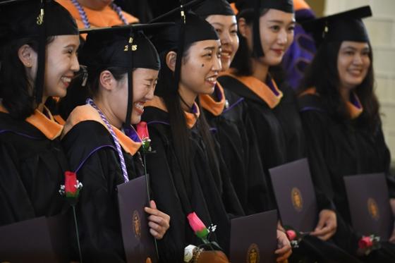 Photo of a group of international students in caps 和 gowns, at a Chatham University commencement ceremony