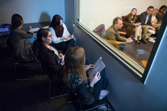 Photo of Chatham University 心理学 students sitting behind a mirrored window observing a therapy session. 