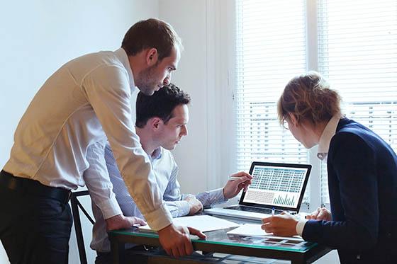 三名商务人士围着一台电脑的照片, working together on a project.