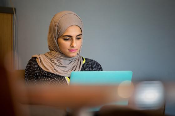 Photo of a female 查塔姆 University wearing a hijab working on her computer in Cafe Rachel