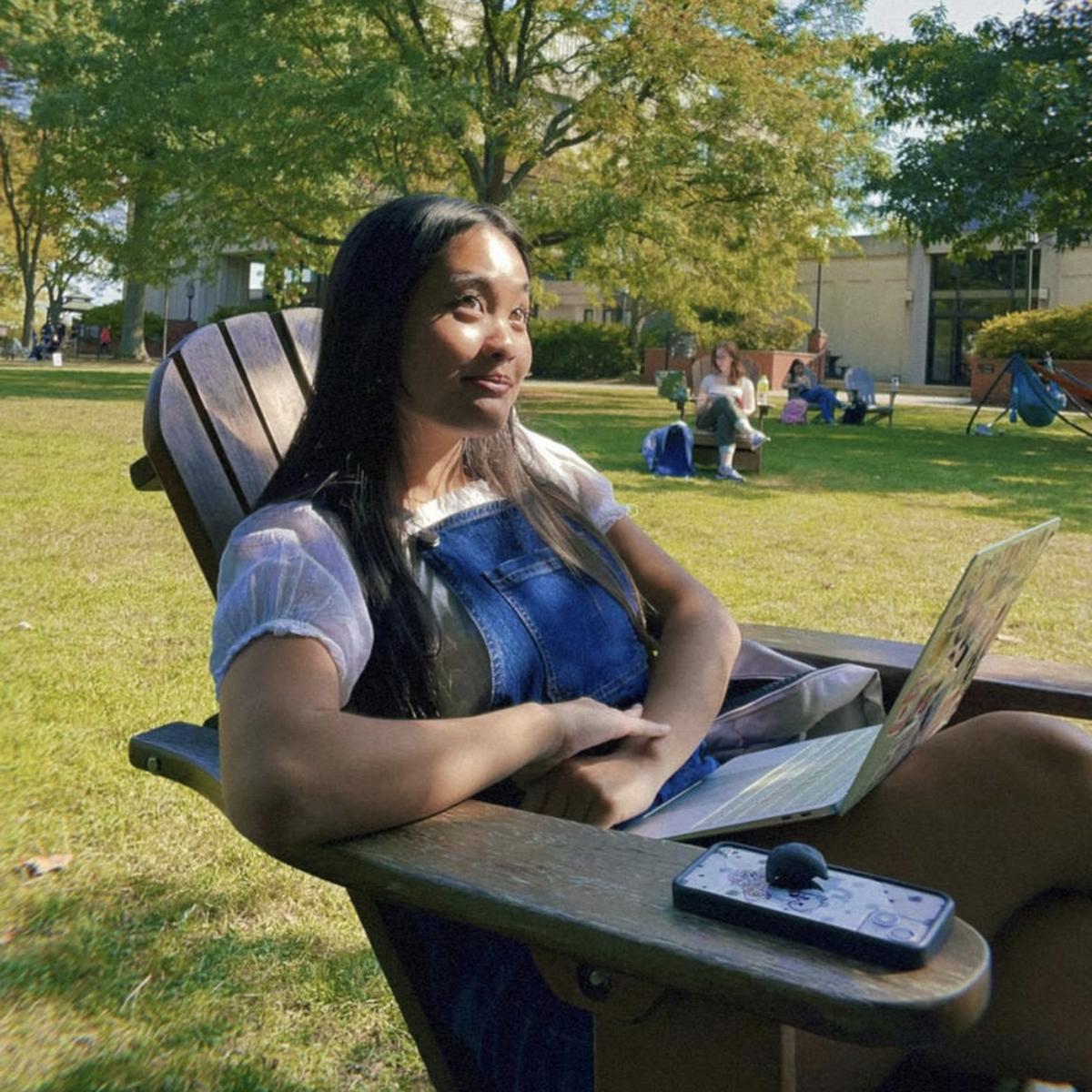 Jolie Phan sits and smiles in an Adirondack chair on 足球波胆平台's quad 