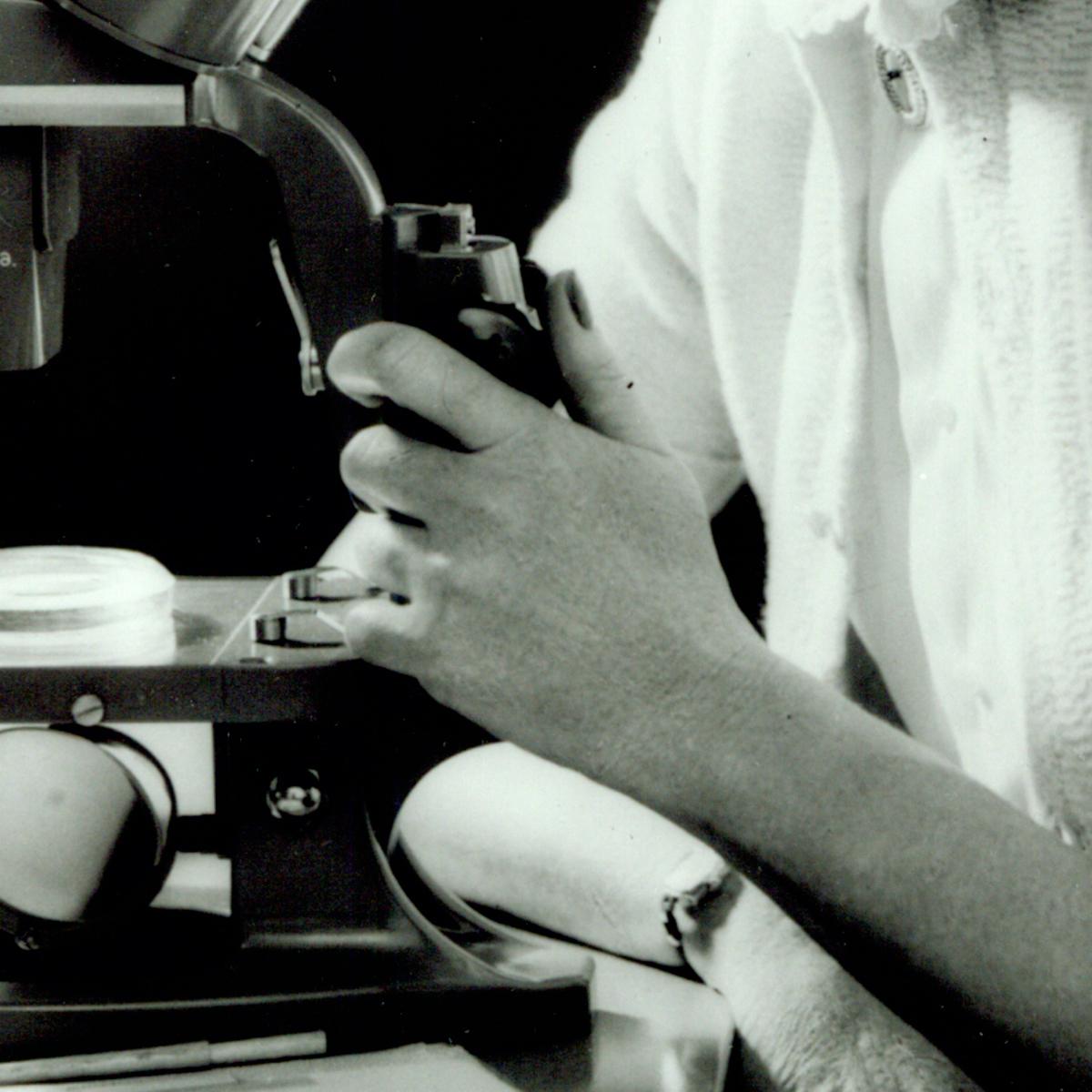 Close-up black 和 white photo of Rachel Caron's h和s operating a microscope